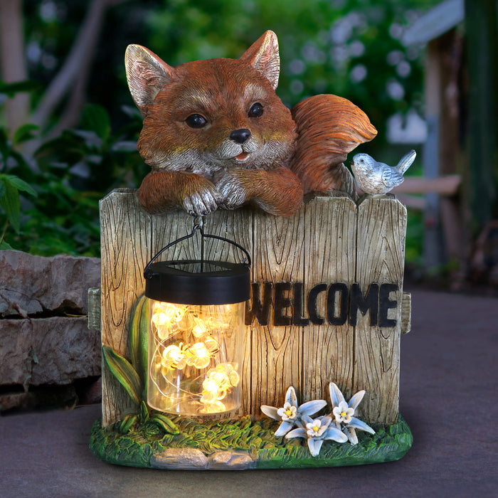 Solar Hand Painted Fox Garden Statue with a Lantern Jar of LED Bumblebees by a Welcome Fence, 9.5 by 11 Inches